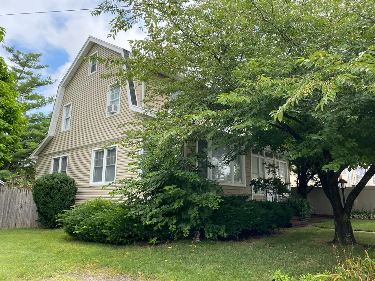 Selling a rental property in Baldwin: two-story colonial behind a leafy front-yard tree