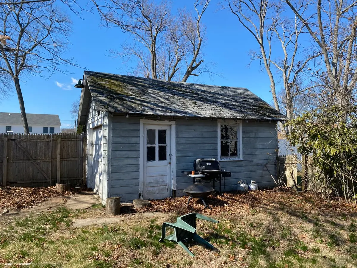 Selling a house as-is in Baldwin: weathered backyard shed with peeling paint